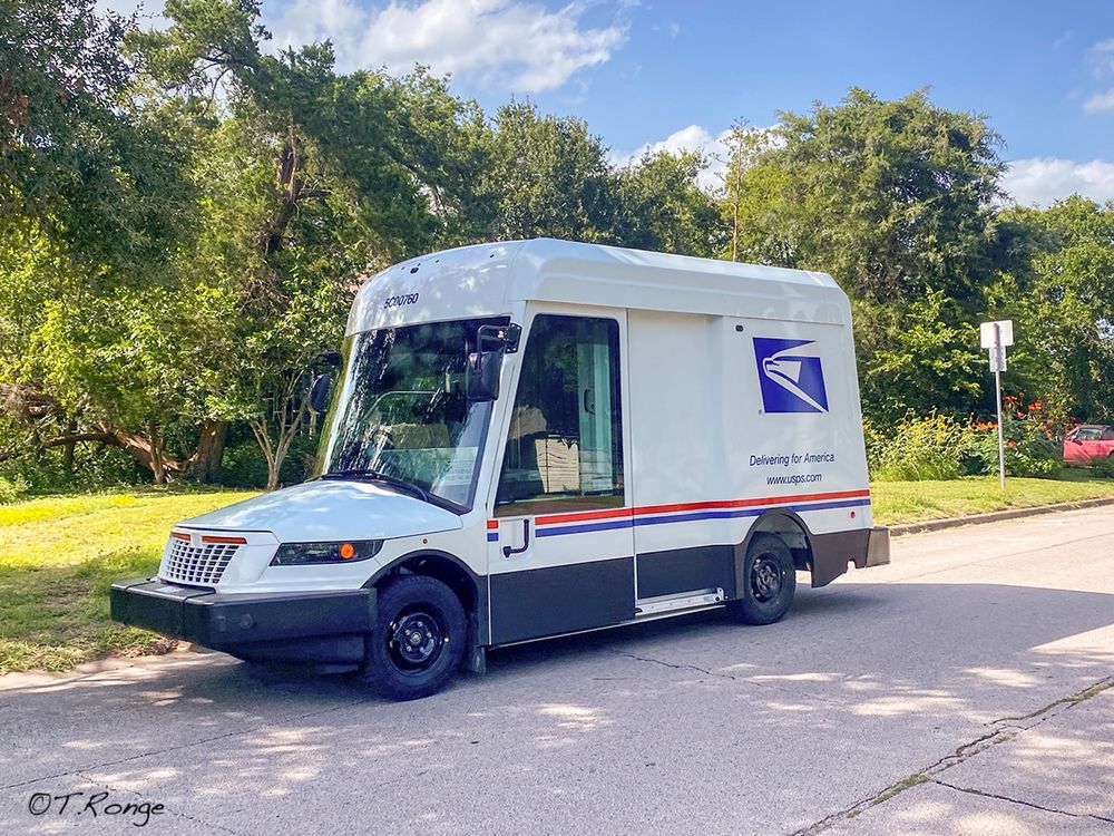 A new USPS electric truck delivering mail.