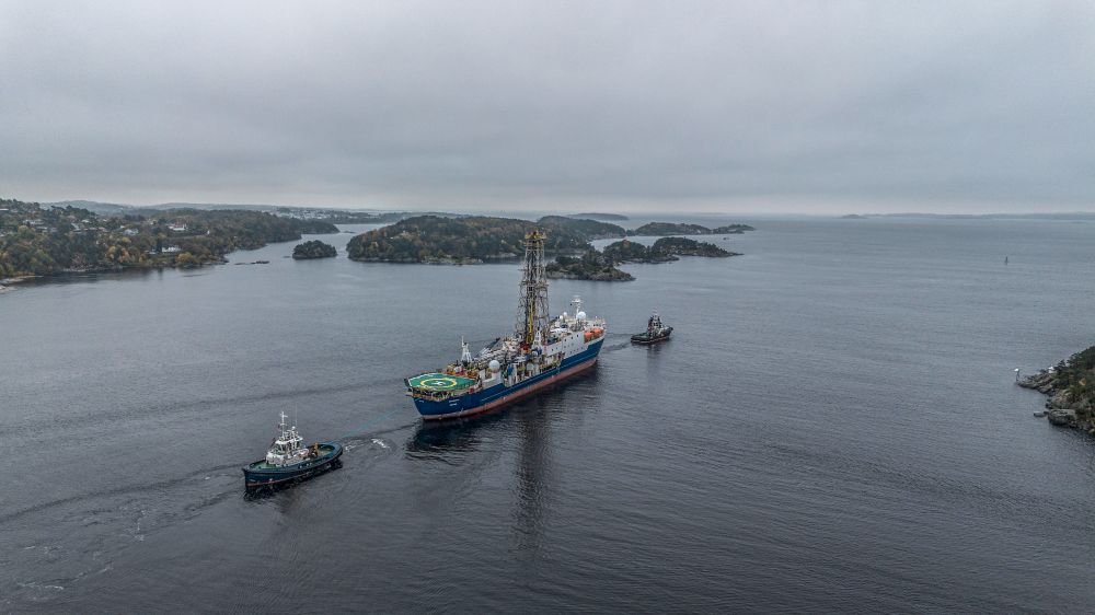 The former IODP research drillship JOIDES Resolution being pulled by two tug boats in a Norwegian fjord. 