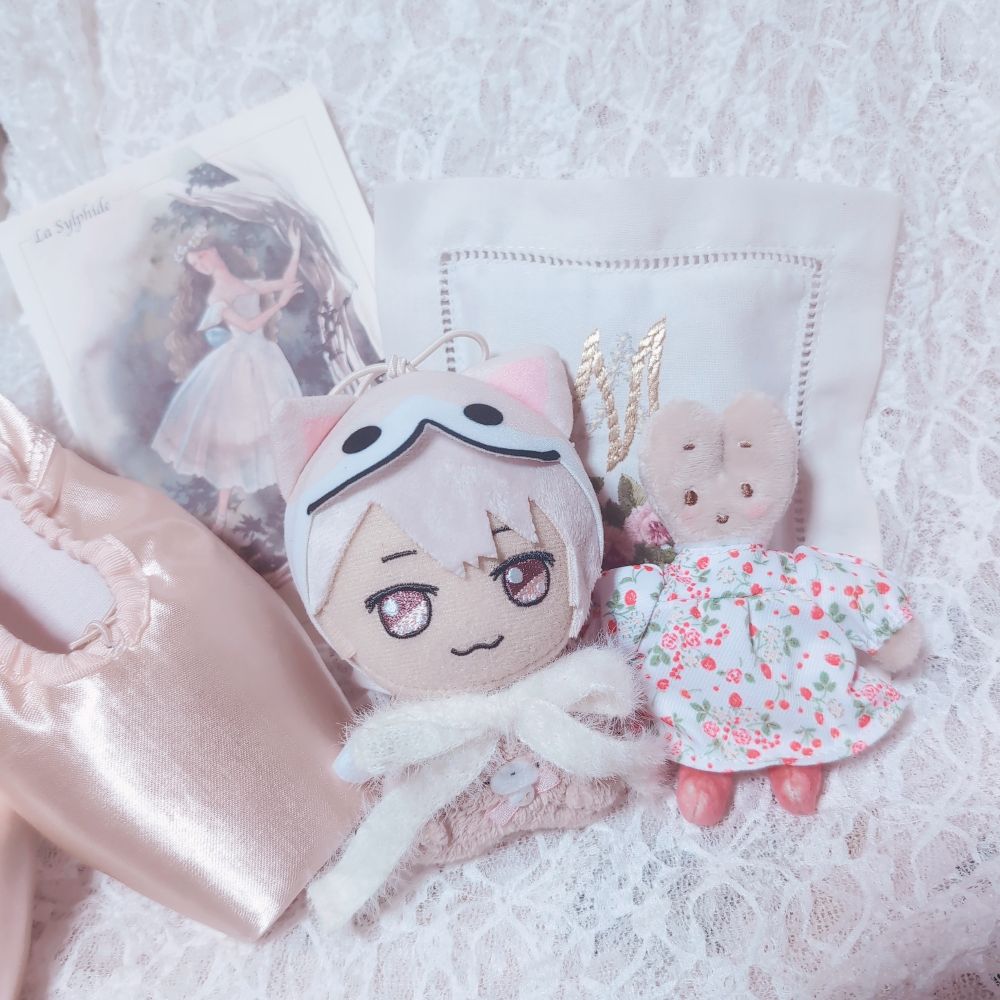 ぬいぐるみ2体とバレエシューズ、バレエ衣装のイラストカード、刺繍入りの布がレースの上に並べられている。カードには「La Sylphide」と記載。ぬいぐるみはアイドリッシュセブンのドンぬい巳波、マロンクリーム。