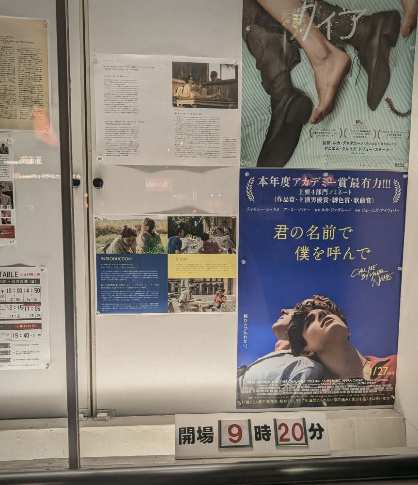 映画『君の名前で僕を呼んで』のポスターと紹介文が掲示されたショーケース。ポスターには空を見上げる二人の青年と「君の名前で僕を呼んで」「4/27(金)」などの文字。下部に「開場 9時20分」の表示。