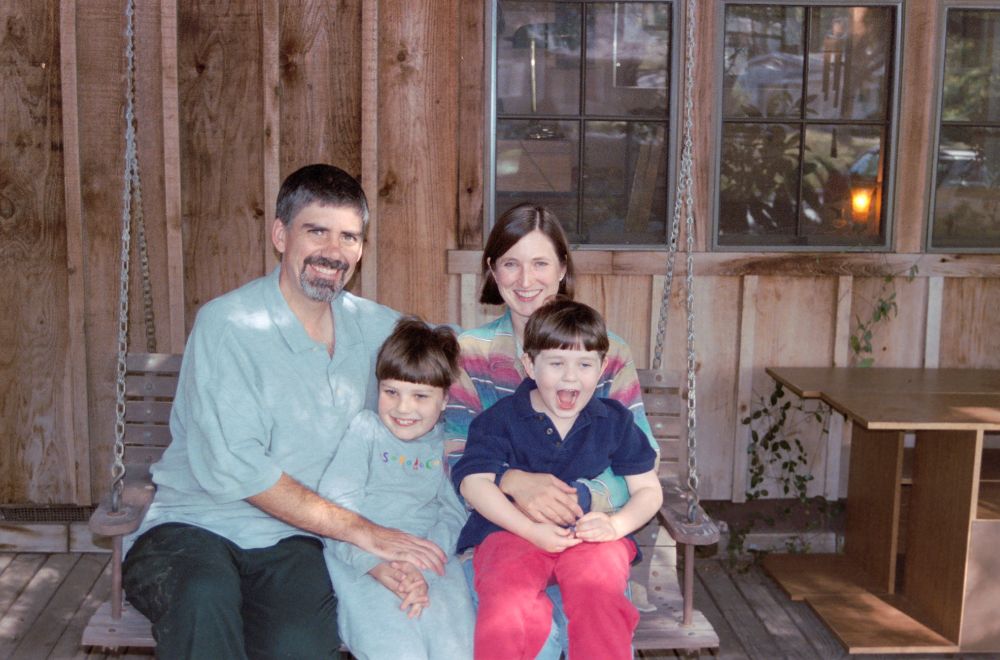 Rick and Becky with sons Haley and Patrick, all smiling from a porch swing.