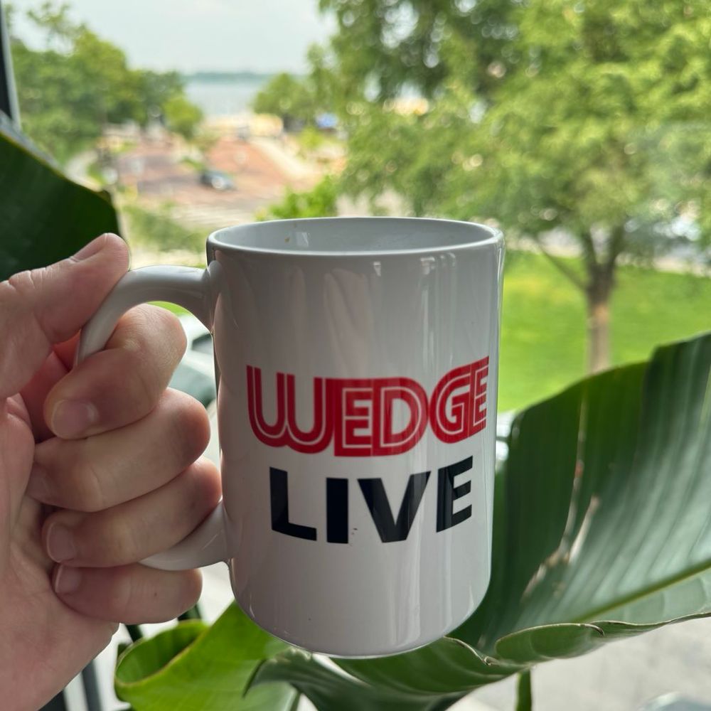 Wedge Live coffee mug being held in front of Bde Maka Ska in Minneapolis 