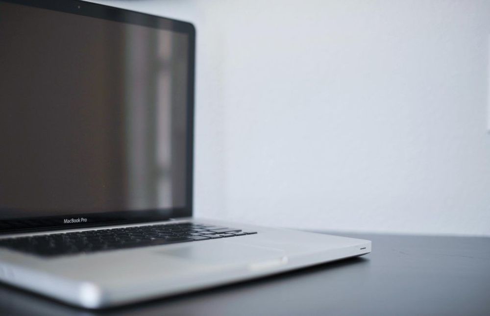 An open laptop with a blank screen in front of a light grey background