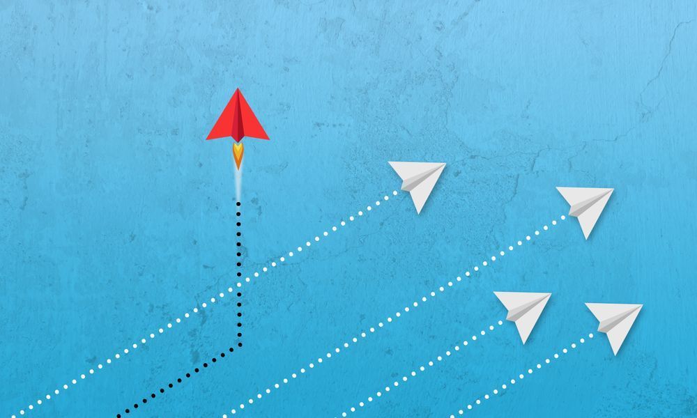 A decorative image of white paper planes flying diagonally with one red plane on a vertical trajectory, to illustrate the boost that an SSCR career development could offer to your career.