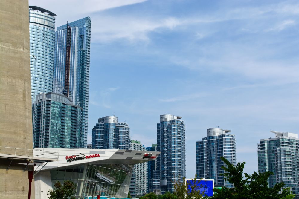 A photograph of steel and glass highrises against a slightly cloudy blue sky. The entrance to Ripley's Aquarium Canada at the lower left part of the photo. 