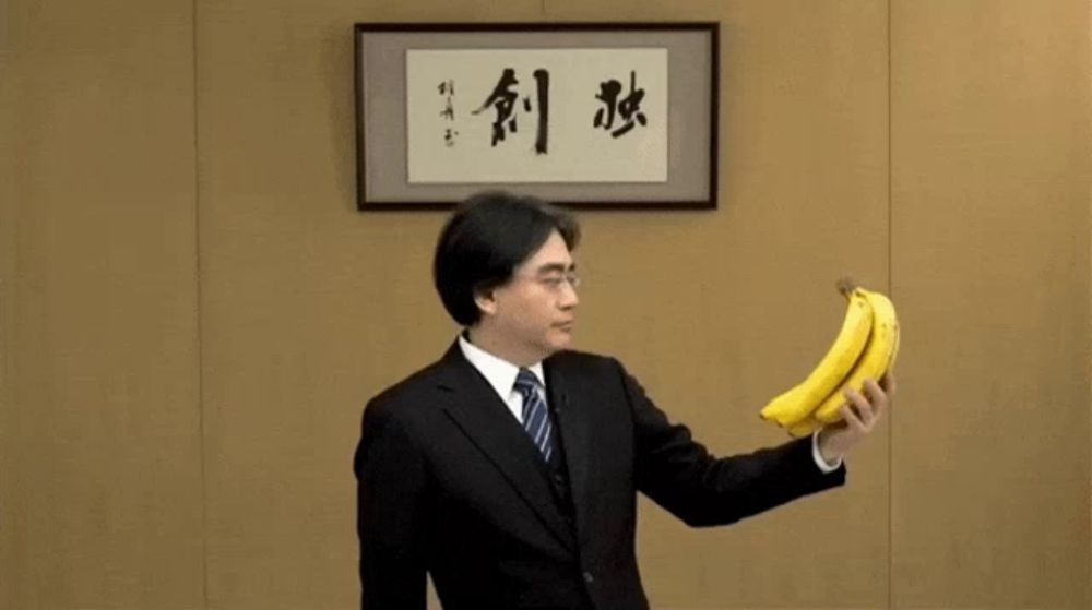 a man in a suit and tie holds a banana in front of a framed picture with chinese writing on it