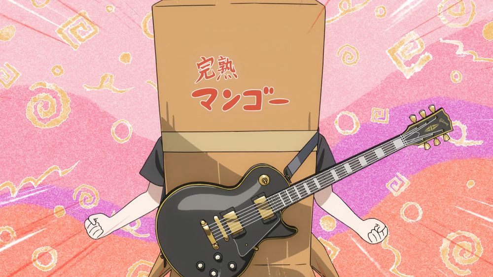 Image de la série Bocchi The Rock! où Bocchi se tient debout cachée dans un carton avec une guitare autour d'elle. Elle prend une pose comme si elle chargeait son énergie