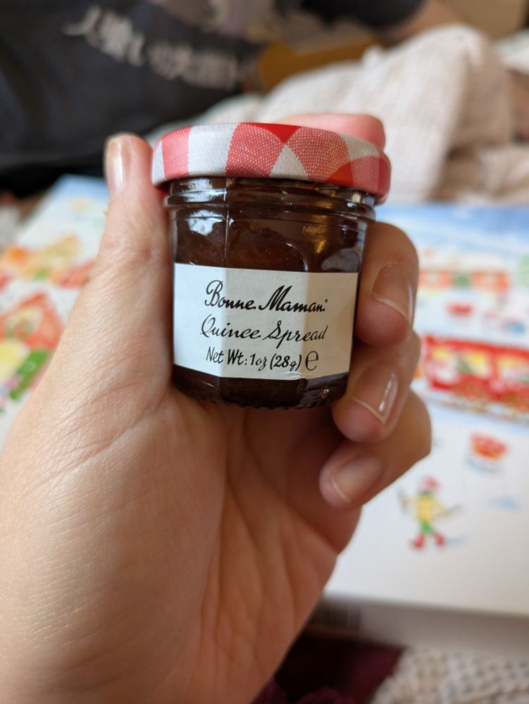 Small jar of jam, label reads, Bonne Maman Quince Spread Net Wt. 1 oz (28 g), held in a hand 