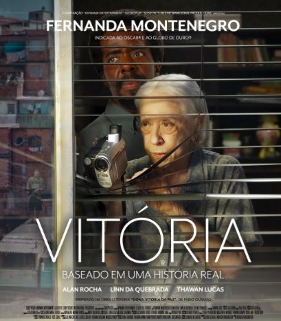 Cartaz do filme "Vitória" com Fernanda Montenegro. Na imagem, ela está numa janela, olhando pra fora, ela empurra a persiana pra baixo e enfia uma pequena câmera de vídeo para filmar algo. O filme tem também Alan Rocha, Linn da Quebrada e Thawan Lucas