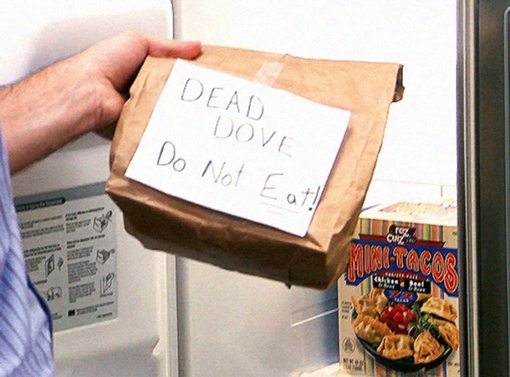 a person holding a bag with a note that says dead dove do not eat