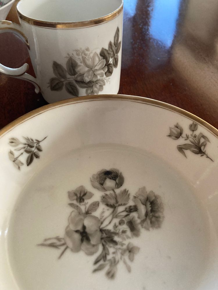 White porcelain cup and saucer, gilt edge, painted in pale grey with a bouquet and smaller sprays of flowers 