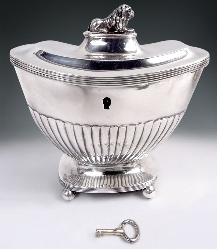 Rectilinear with tapering bowl and concave top, base on four corner balls; cover hinged and double-domed with cast finial in the form of a lion couchant