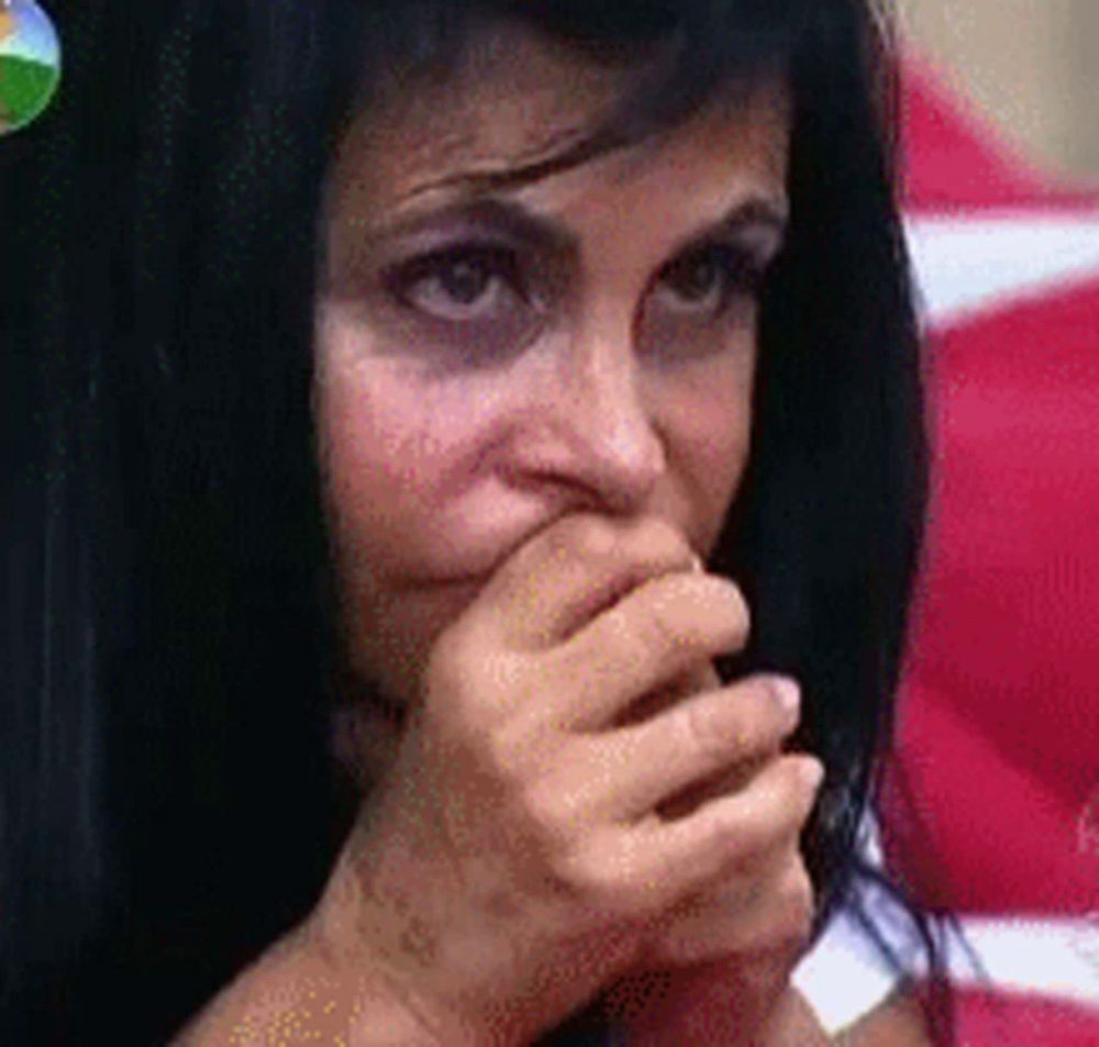 a woman with black hair is covering her mouth with her hand