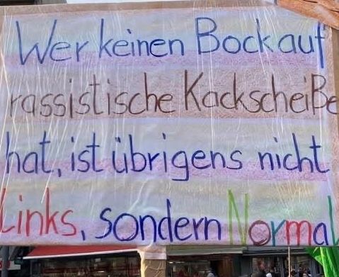 Demoplakat mit dem Text " Wer keinen Bock auf rassistische Kackscheiße hat, ist übrigens nicht links, sondern normal!"