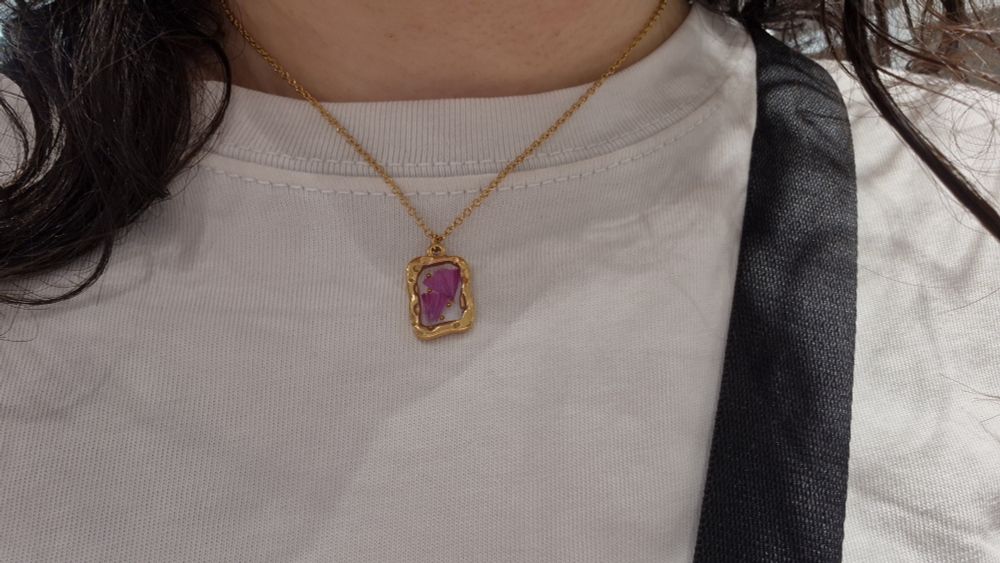 Collar dorado en forma rectangular pequeña con flor morada