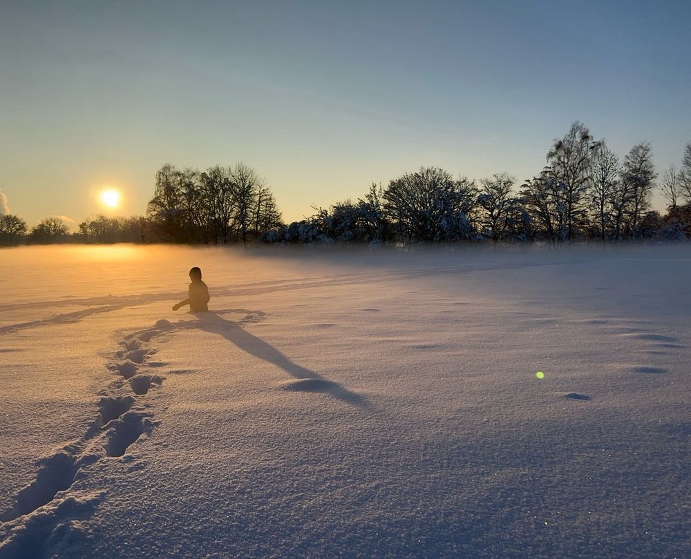 Mensch im hüfthohen Schnee bei Sonnenuntergang