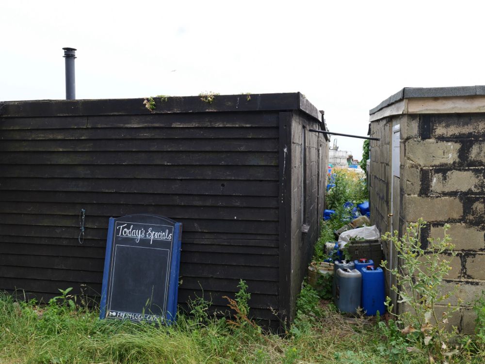 Today’s Specials sign against a black wooden shack and a view of the path between it and the next building