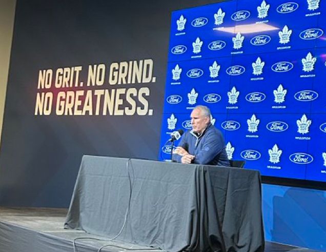 Craig Berube speaks to the media after the Leafs were eliminated from the 2025 Stanley Cup playoffs in front of a sign that reads "No Grit. No Grind. No Greatness." which is meant to be inspirational but instead is the most on-point thing ever written.