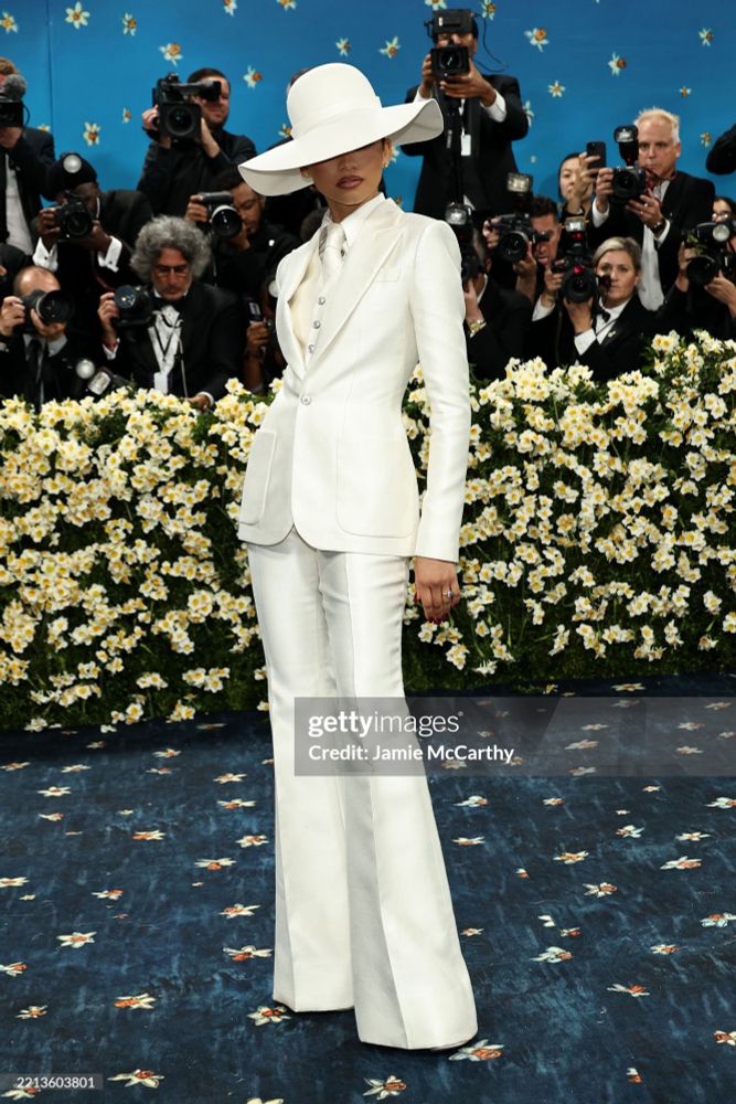 zendaya at the met gala in a sleek white suit and flowing hat