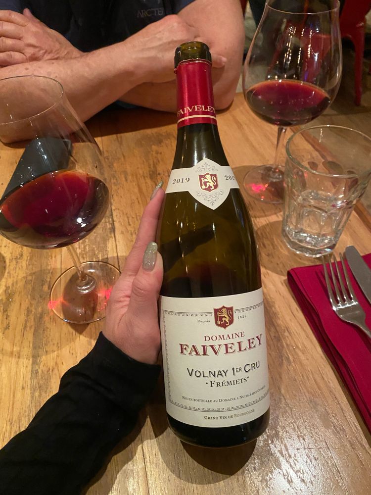 On a romantic dinner date, Celeste holds the bottle of 2019 Domaine Faiveley Volunay 1er Cru wine the pair are enjoying