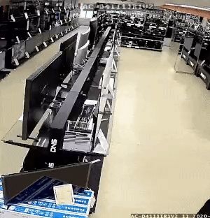 man walking along a television isle of a hardware store: hitting every television with a hammer, some of them fall over, nobody is even stopping him. the video has been sped up for comedic effect.