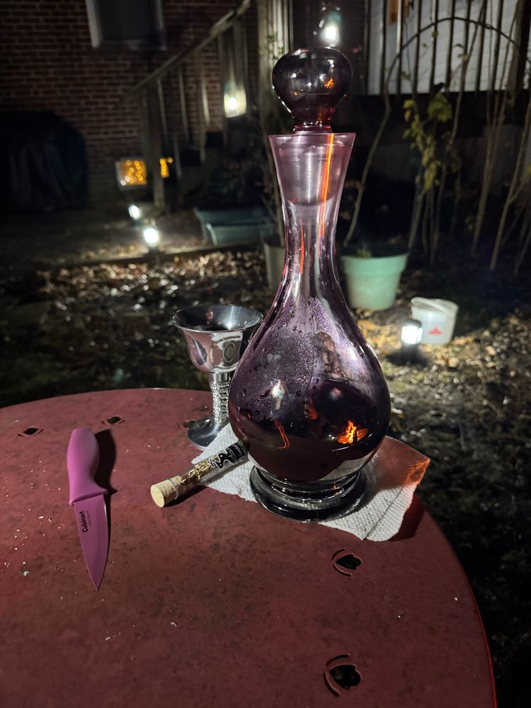a decanter with red wine, a vial of of herbs, a goblet, and a knife