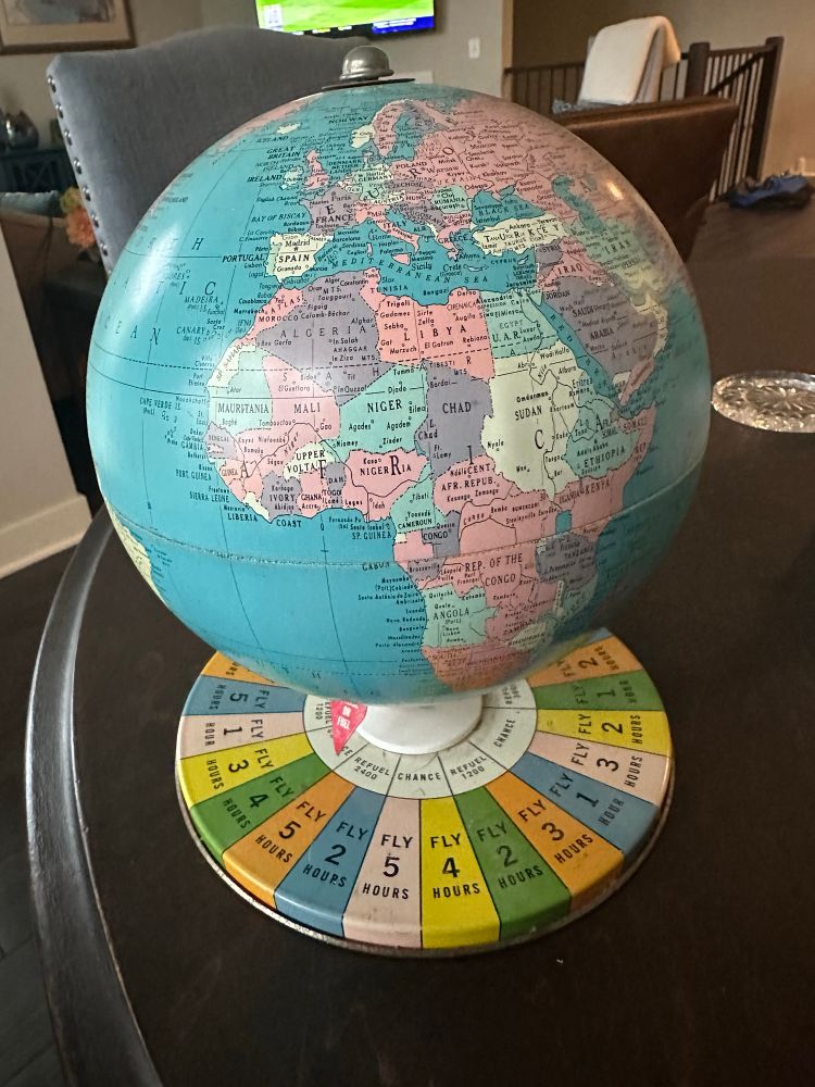 An antique globe with a board game base on a table