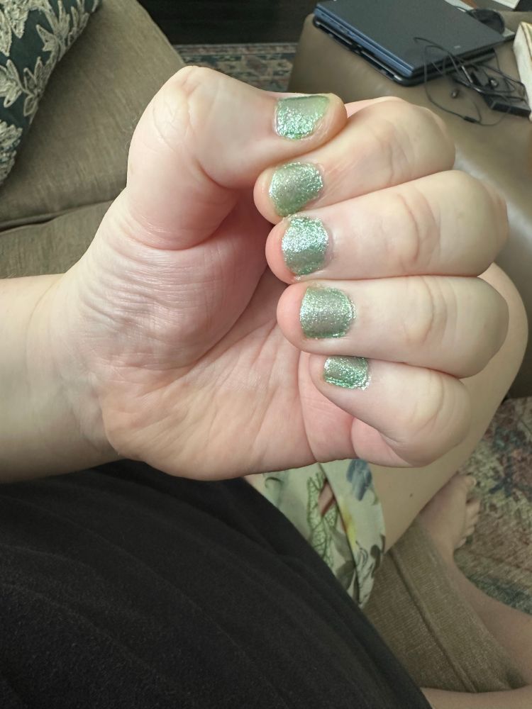 Robin’s hand with her nails painted a sparkly sage green color
