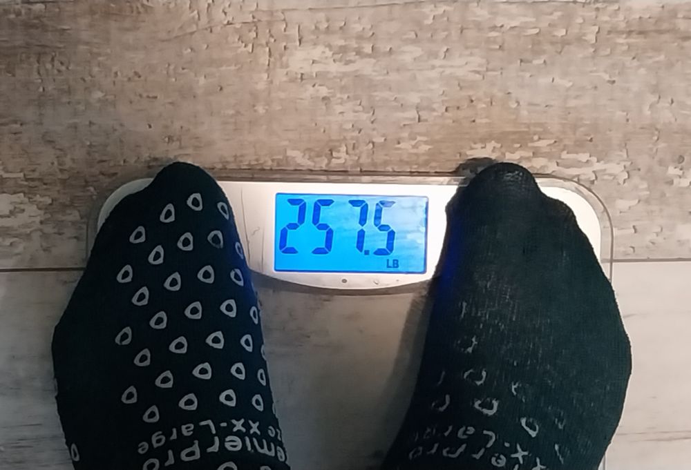 A person stands on a scale reading 257