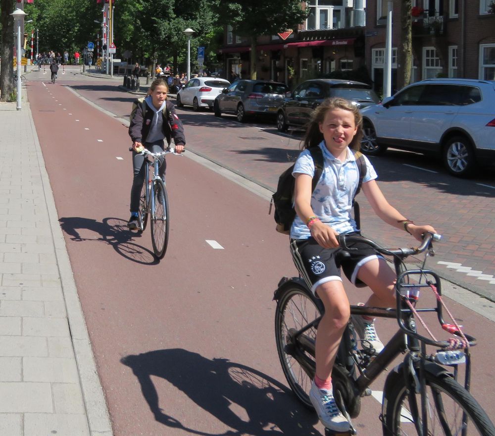 Two young female children cycle on a protected cycle track 