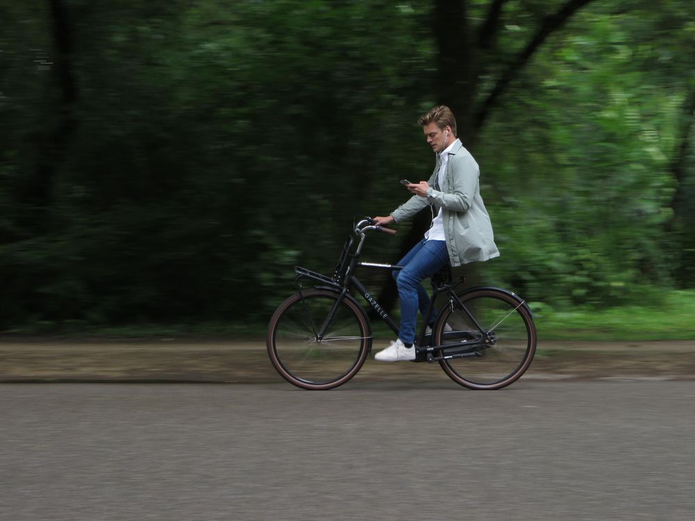 A man cycles listening to music on his phone 