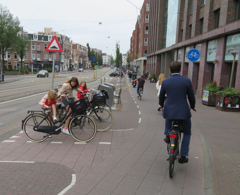 A man cycles in a suit on a protected cycle track 
