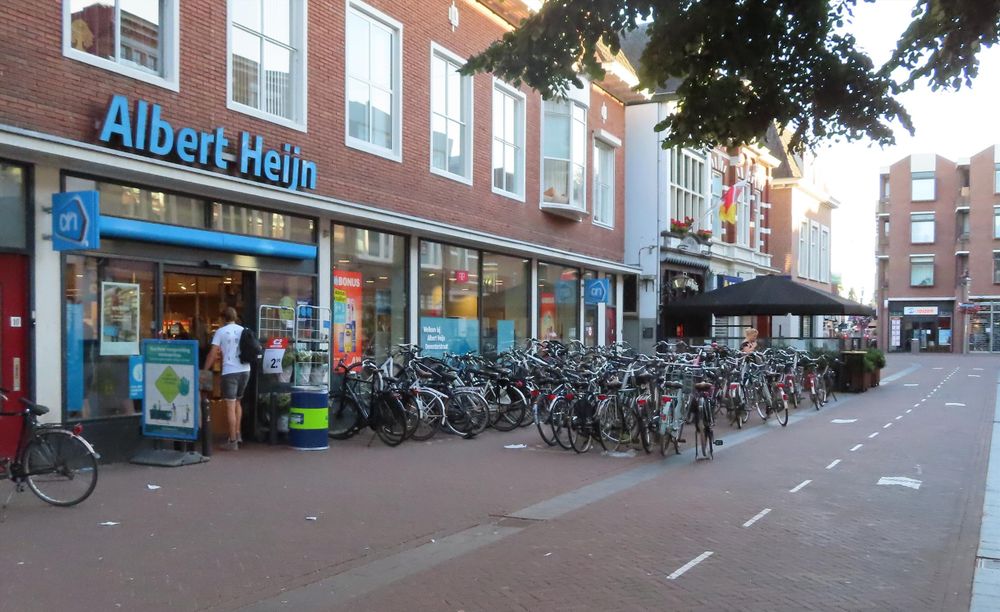 Parked bikes and bike stands outside an Albert Heijn Supermarket in the Netherlands 