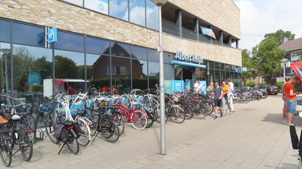 Parked bikes and bike stands outside an Albert Heijn Supermarket in the Netherlands 
