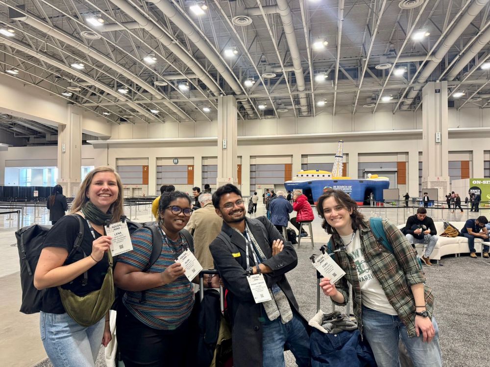 4 people smiling while showing off their conference badges. 