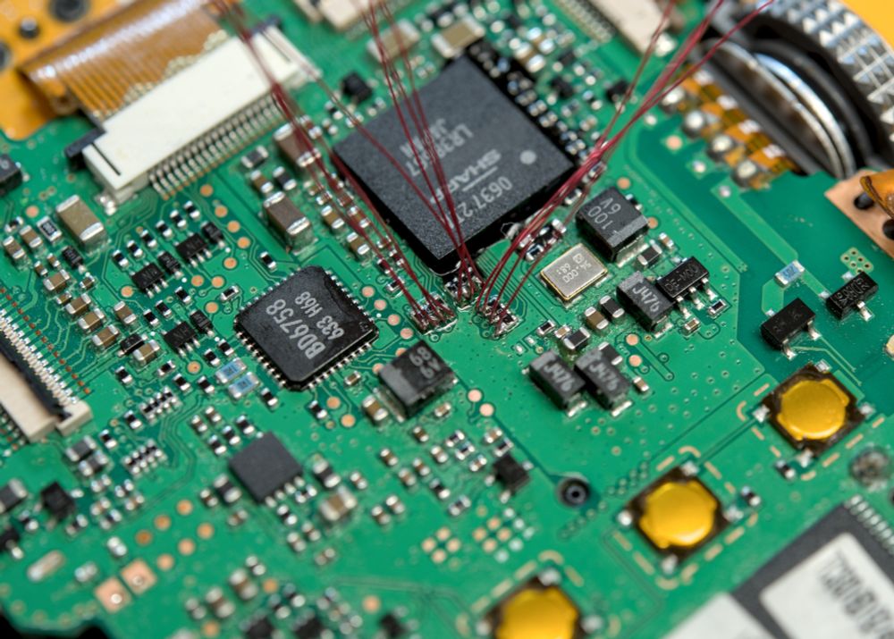 A zoomed in photo of the mainboard on a Samsung Digimax S500 showing 12 strands of magnet wire soldered to the legs of three SMD resistor networks 