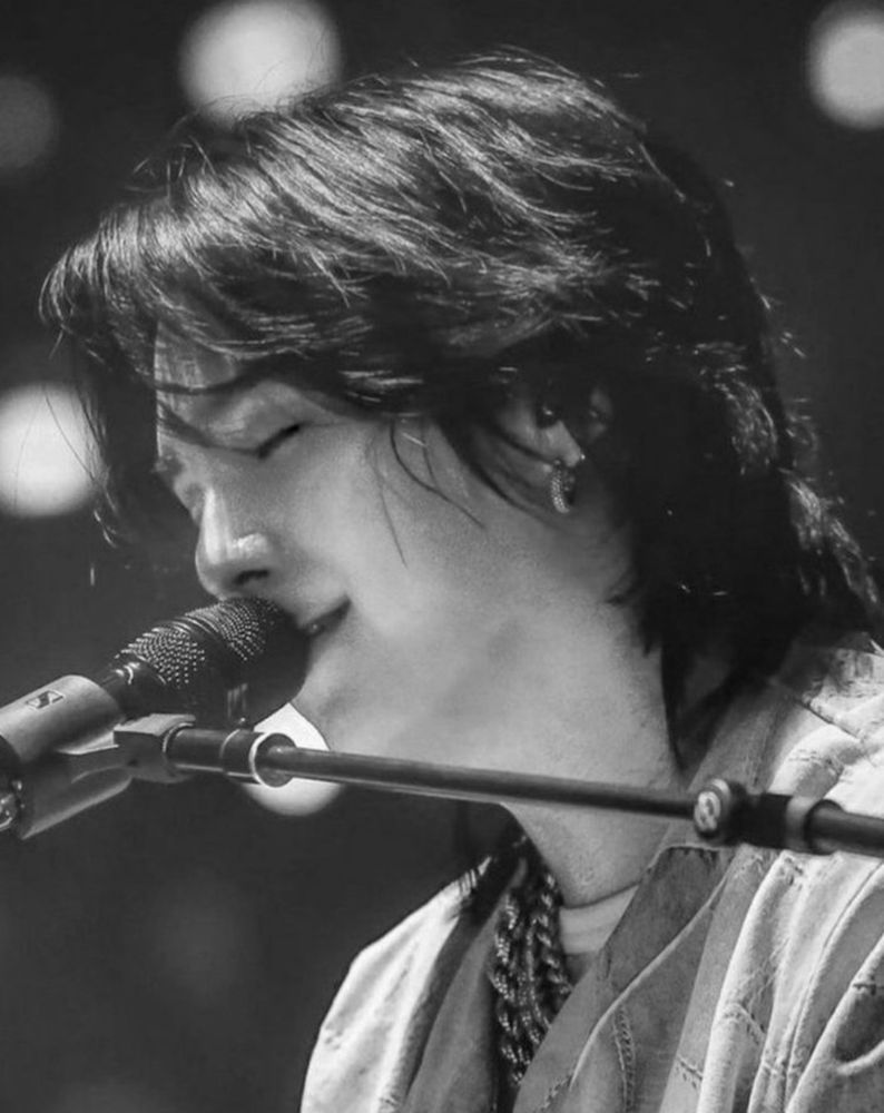 beautiful black and white of Yoongi, softly smiling as he sings into a mic.