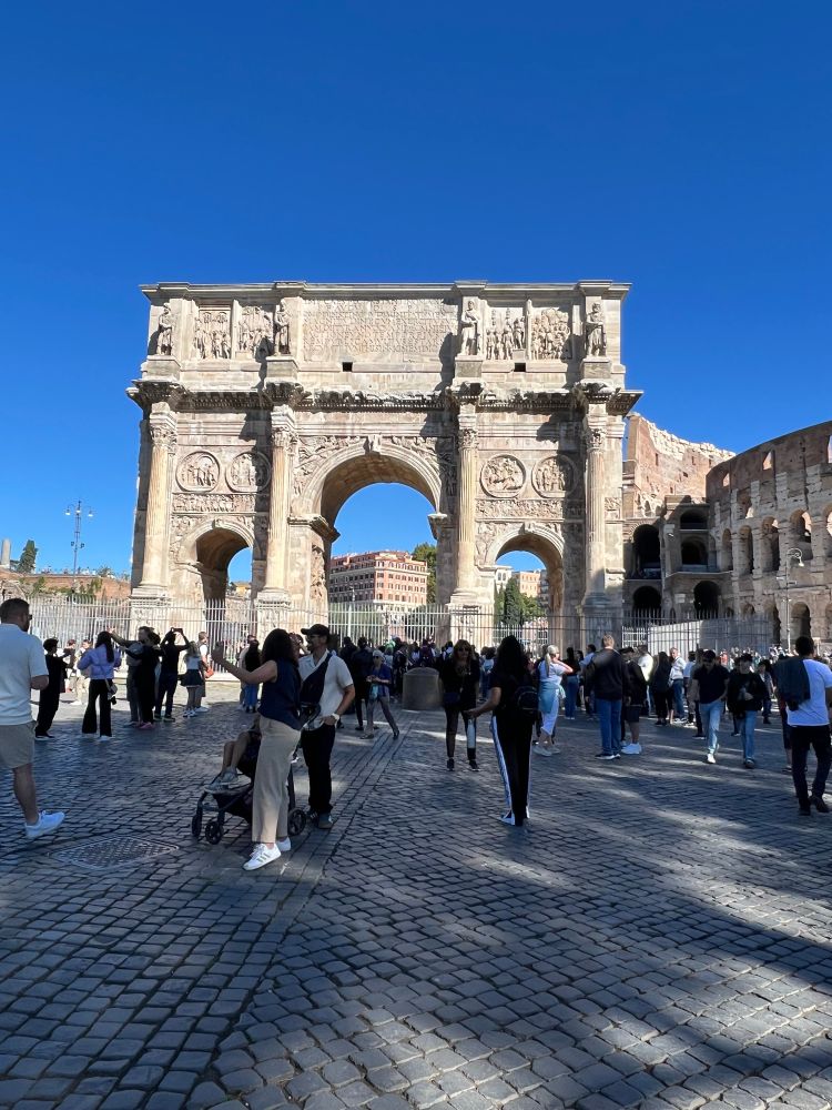 The arch of Constantine with coliseum beside and lots of people.