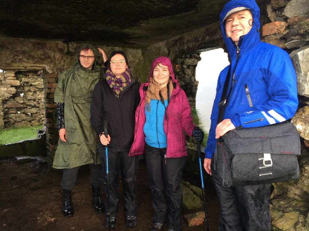 Two men and two women happy to shelter from the rain in a sheep shed (stone walls with no doors and a dirt floor).