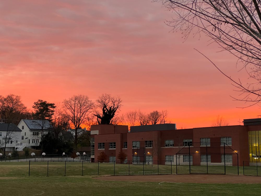 Red sky over s playing field and two story building.