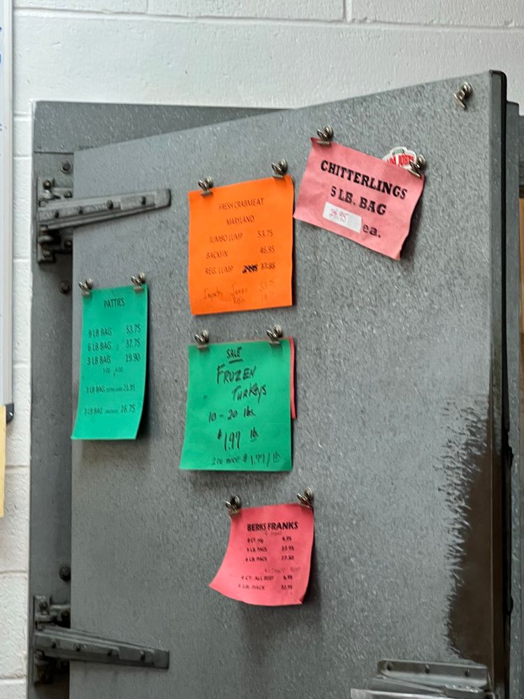 A door to a cold room advertises a 5 lb bag of chitterlings for 24.95; frozen turkeys; crabmeat; berts franks and patties.