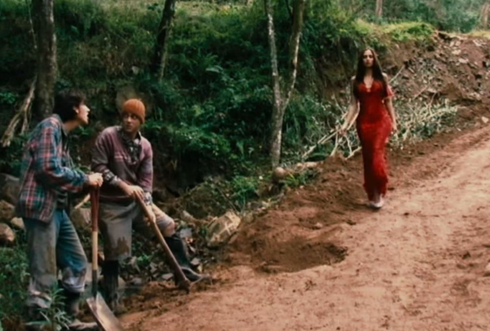 Imagem da personagem Silene Seagal, uma mulher de vestido vermelho comprado na Só Lindezas indo a sua formatura, e dois operários