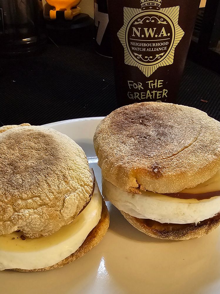 Two homemade egg mcmuffin sandwiches and a pint glass that references the movie "Hot Fuzz"