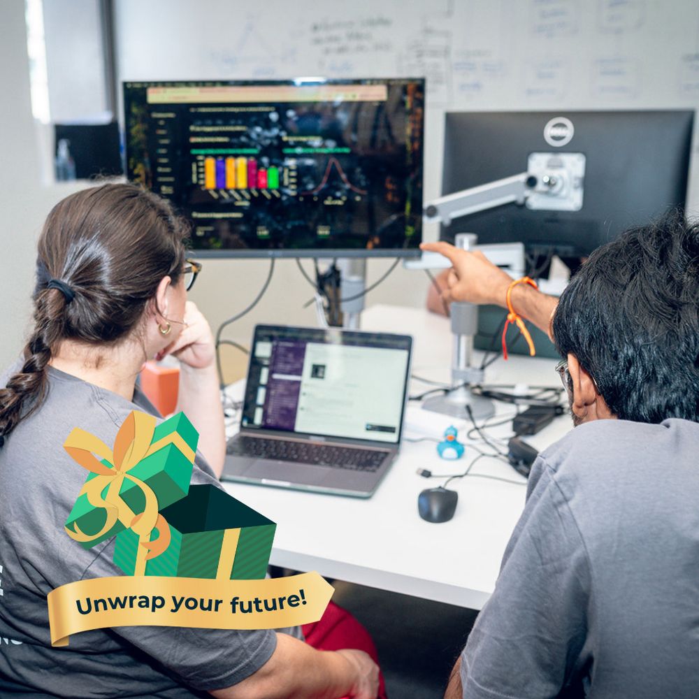 Two Zip Coders looking at computer screens. Green gift box graphic that reads, "Unwrap your future!" in the corner. 