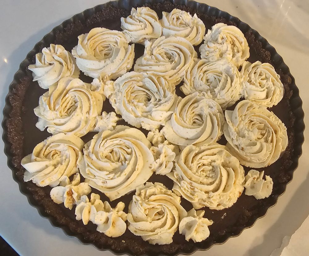Dark chocolate tart with rosettes made with espresso whip cream 
