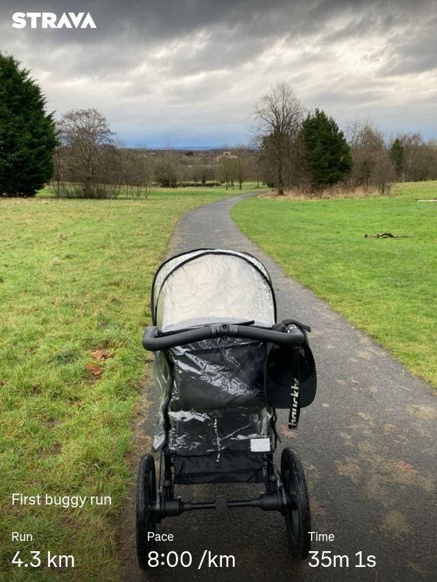 A picture of the running pram on a path in a park. In the background the view of Glasgow’s East End and some cloudy grey skies. On the bottom some Strava stats: First buggy run. 4.3km. 8:00/km pace. 35m1s. 