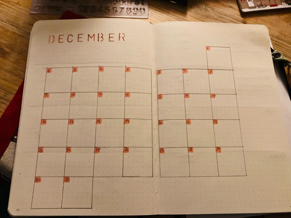 My December overview. It’s a calendar style with square boxes for each day. The top right corner is coloured in in each box to add the date. The calendar is still empty. 