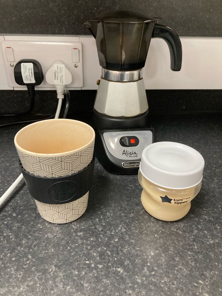 My reusable coffee mug, the electric espresso machine, and a Tommee Tippee 150ml bottle with oat milk covered with a normal screw lid. 