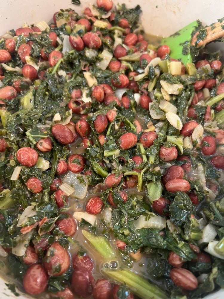 Plump red beans and greens simmering in an enameled pot