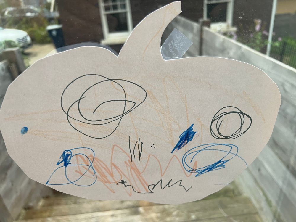 A pumpkin cutout with a spooky toddler drawing 